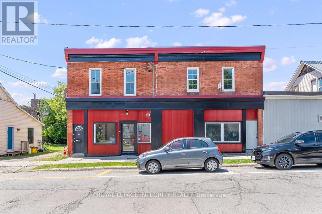 A two-story building with a red and black exterior and a car parked in front.