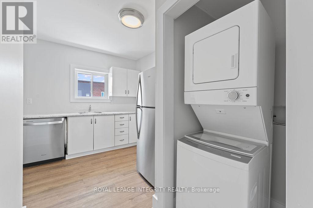 A white fridge in a kitchen with wooden floors and white walls.