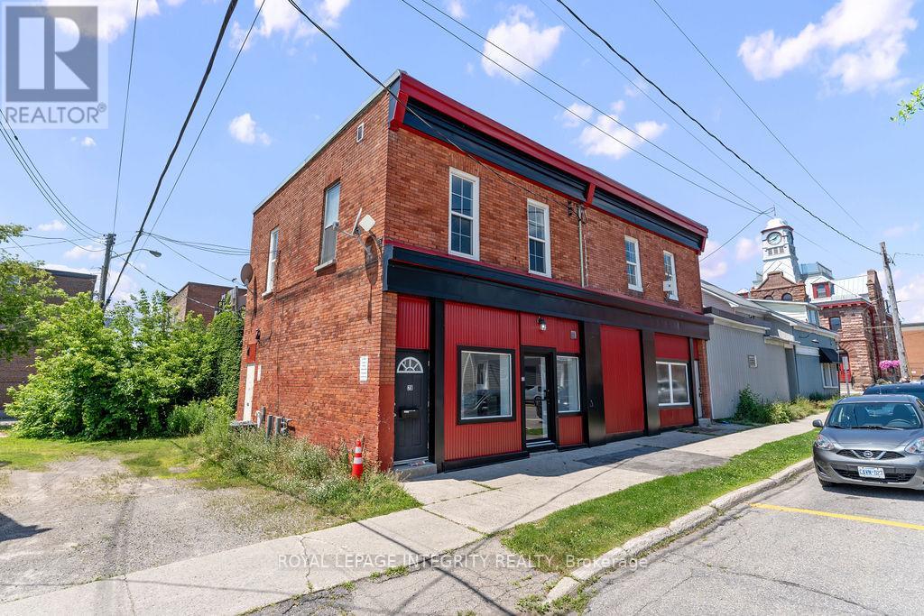 A red brick building with a black door and windows is in front of a street.