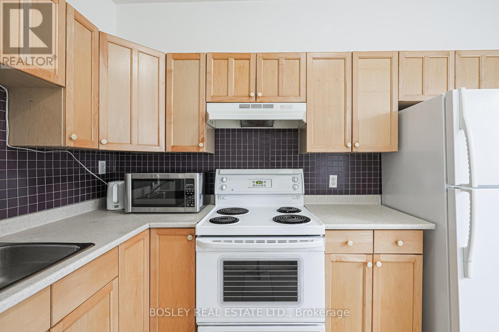 A kitchen with wooden cabinets and a white stove top oven.