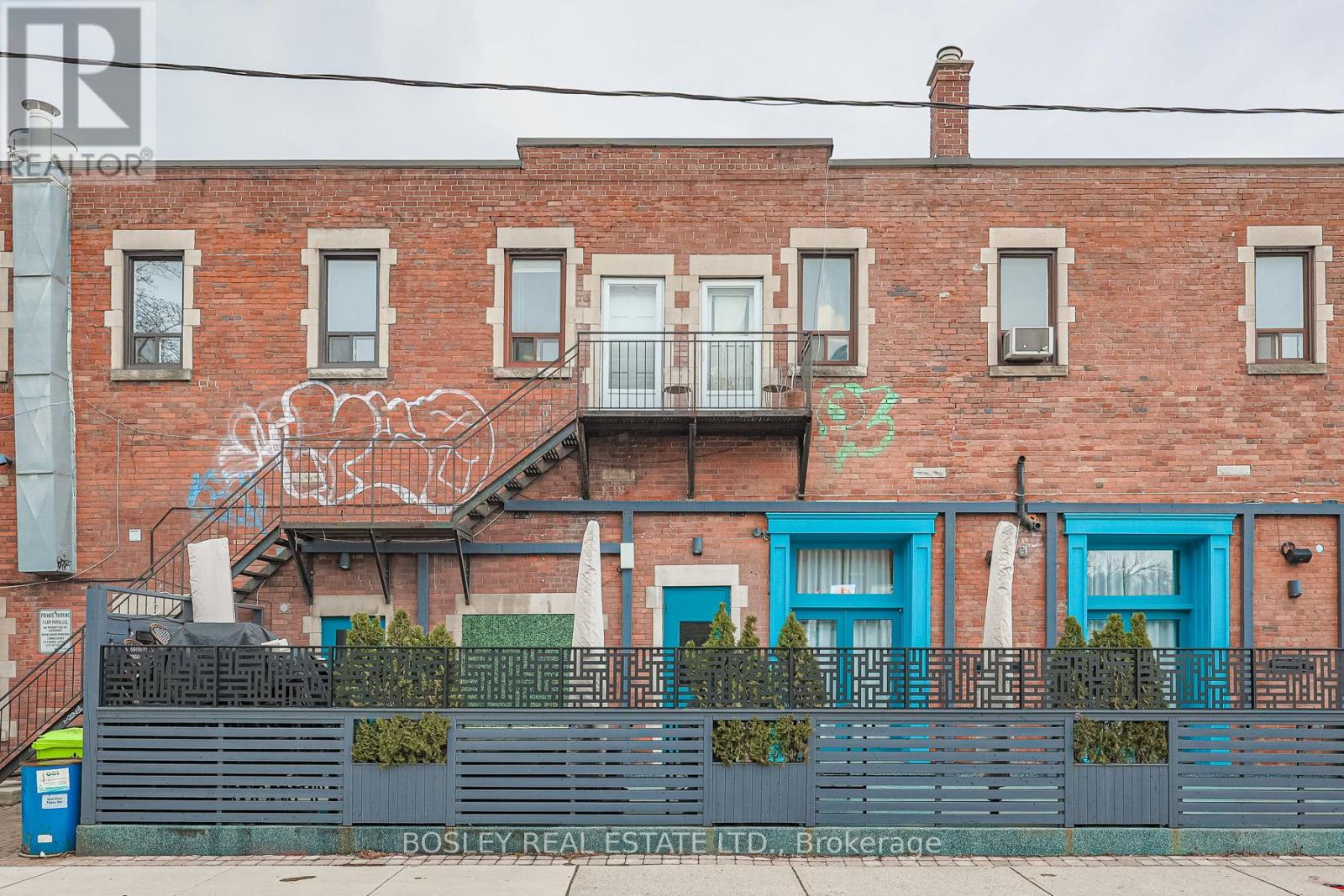 A red brick building with a balcony and a blue door.