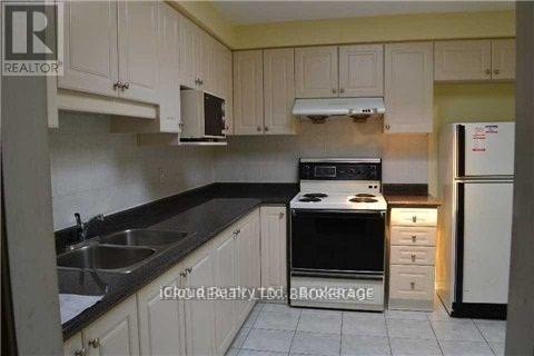 A kitchen with white cabinets and black countertops.