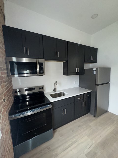 A kitchen with black cabinets and stainless steel appliances.