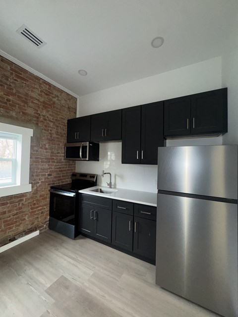 A kitchen with a stainless steel refrigerator and black cabinets.