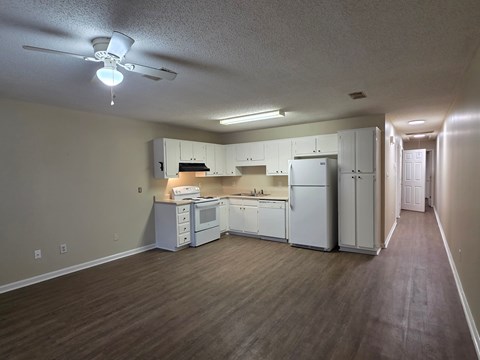 A kitchen with white appliances and wooden floors.