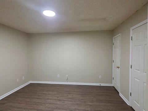 A room with a brown floor and white walls.