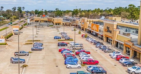 A parking lot with cars parked in rows in front of a shopping center.