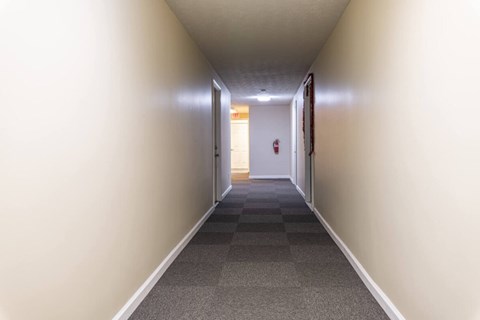 A long hallway with a checkered floor and a door at the end.