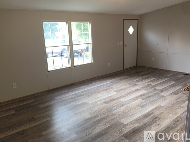 A room with wooden flooring and a door is available.