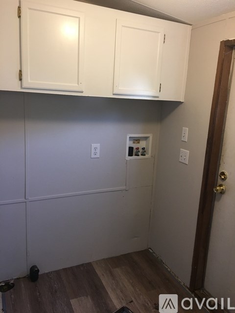 A kitchen with white cabinets and a wooden floor.