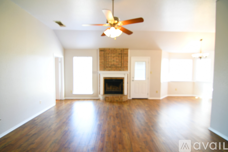 A spacious living room with a fireplace and a ceiling fan.