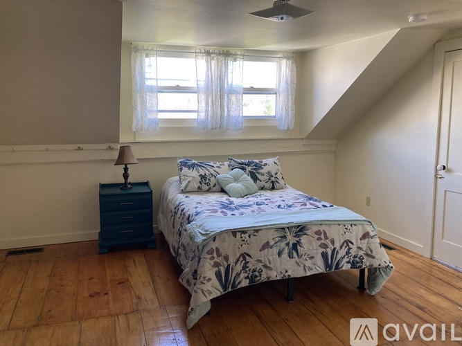A bedroom with a bed, nightstand, and window.