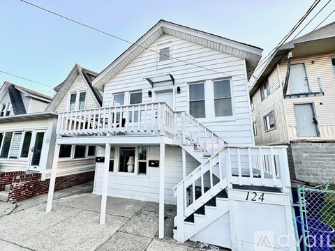 A white two-story house with a balcony and stairs leading to the second floor.