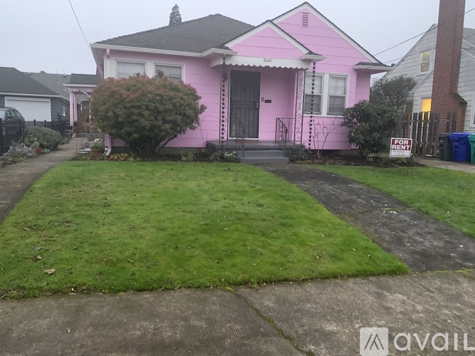 A pink house with a front yard and a "For Sale" sign.