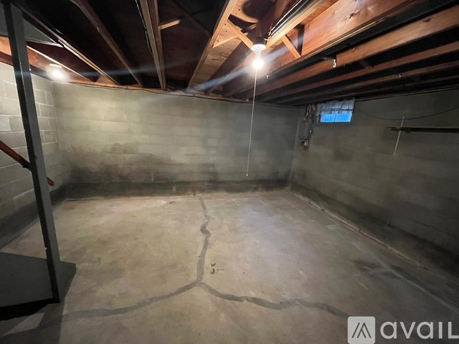 A spacious basement with a concrete floor and exposed wooden beams on the ceiling.