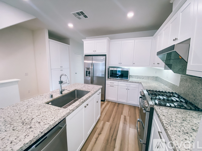 A modern kitchen with granite countertops and stainless steel appliances.