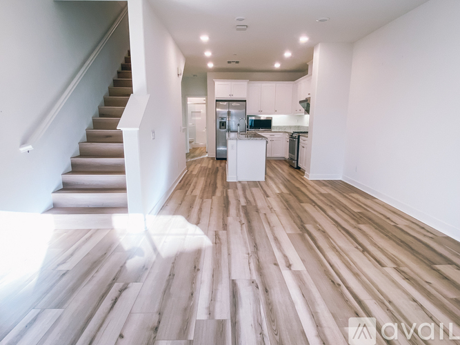 A spacious room with wooden flooring and a staircase leading to another level.