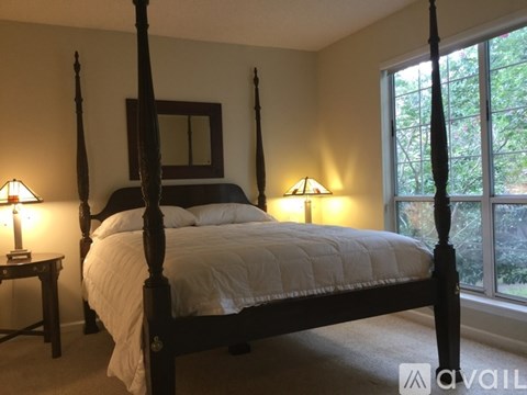 A bedroom with a four poster bed and two lamps.
