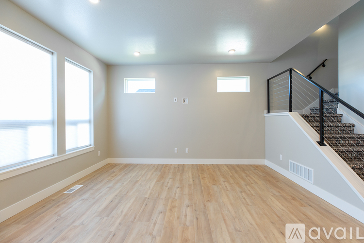 A spacious room with wooden floors and a staircase on the right side.