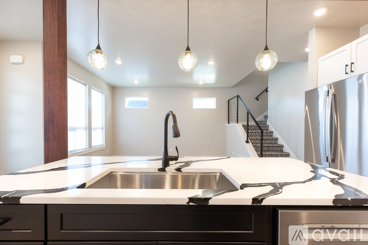 A modern kitchen with a stainless steel sink and black cabinets.