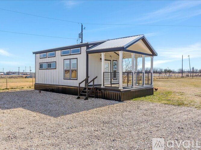 A small house with a porch and a gravel driveway.