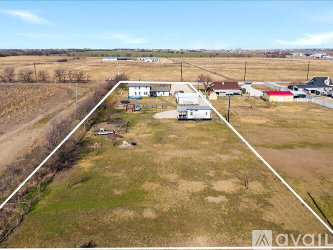 A farm with a white barn and a red building is surrounded by a white line.