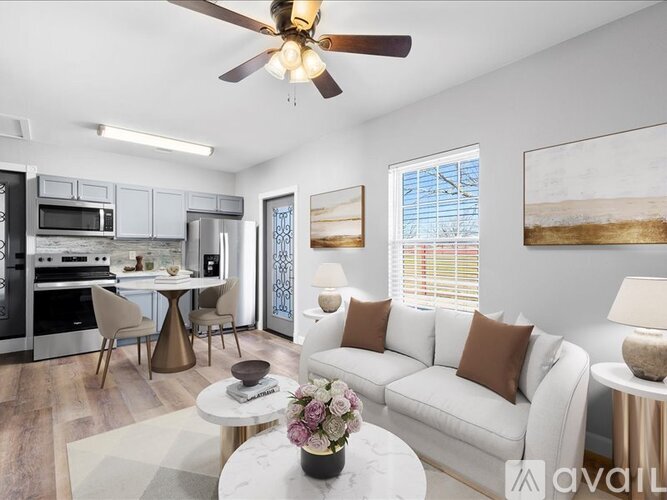 A living room with a white couch, a dining table, and a ceiling fan.