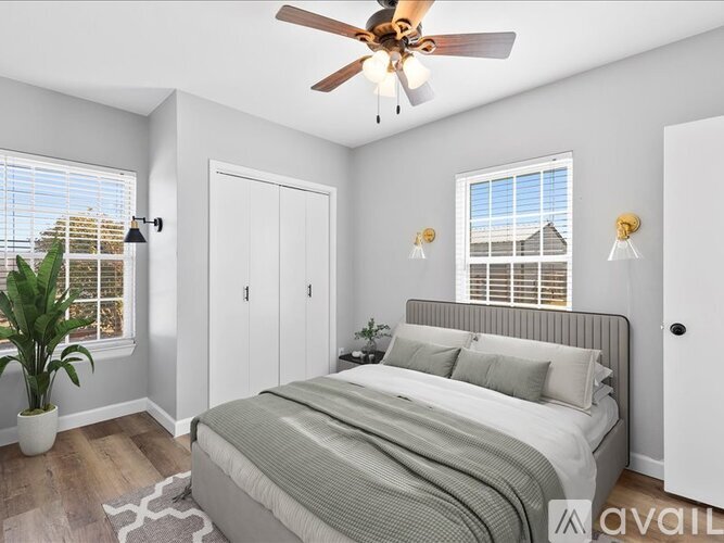 A bedroom with a bed, a ceiling fan, and a window with blinds.