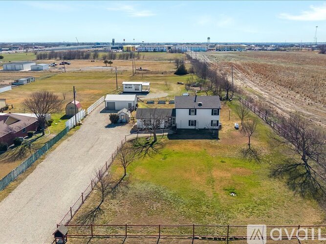 A large open field with a few buildings and a fence.