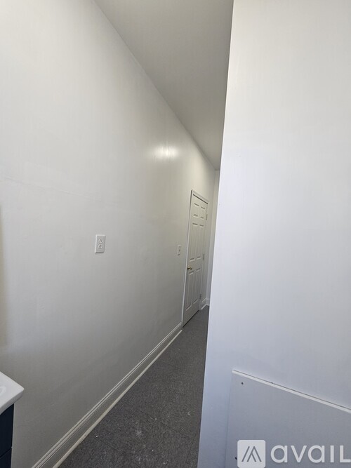 A hallway with a door at the end and a sign on the wall.