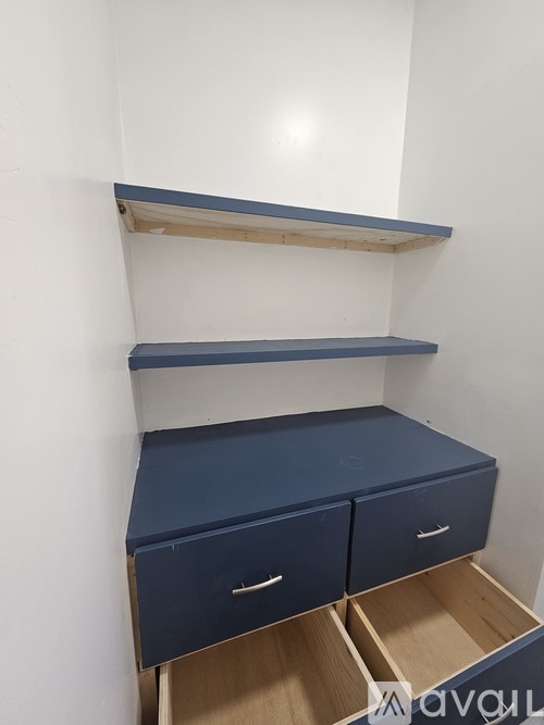 A white wall with a blue shelf and drawers.