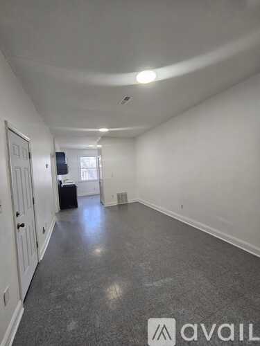 A white toilet in a bathroom with a white wall and grey floor.