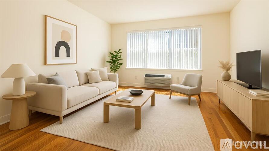 A living room with a white couch, a wooden coffee table, a white chair, a white floor lamp, a white rug, a white wall with a framed picture of a person, a window with white blinds, a green plant,