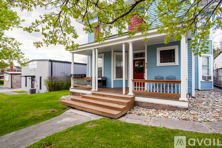 A blue house with a porch and a red door.
