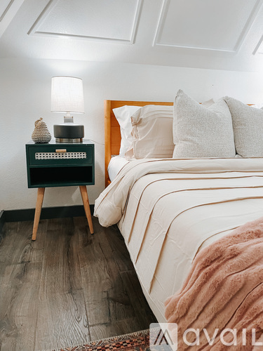 A bedroom with a bed, a nightstand with a lamp and a decorative item on it.