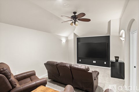 A living room with a brown leather couch and a flat screen TV mounted on the wall.