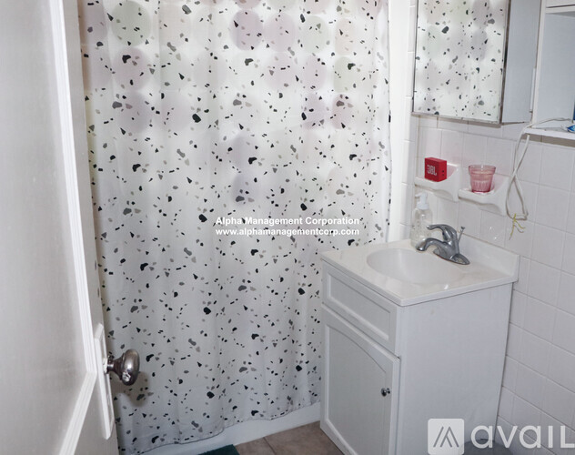 A bathroom with a sink, mirror, and shower curtain.