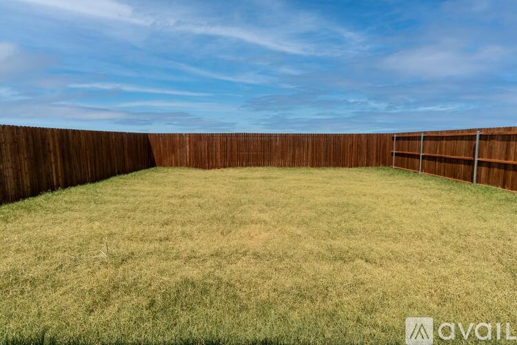 A backyard with a wooden fence and grass.
