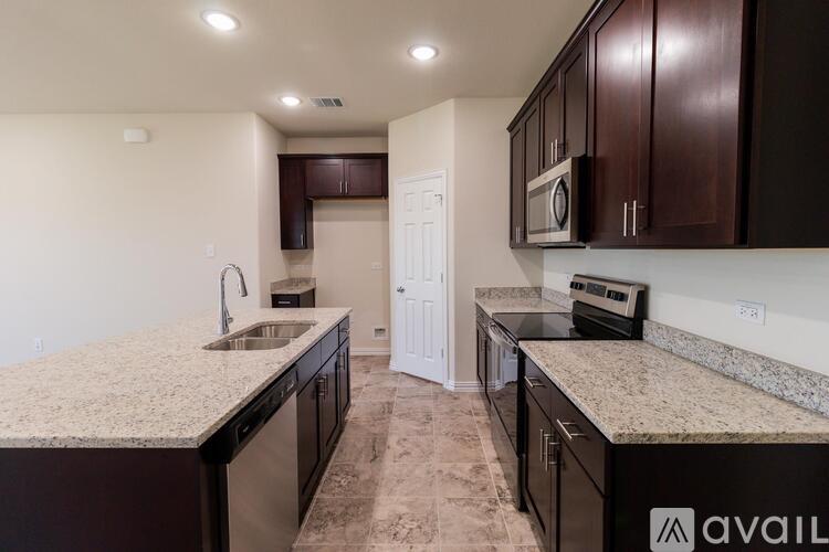 A kitchen with granite countertops and dark wood cabinets.