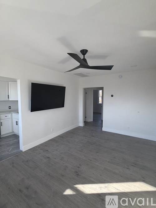 A room with a ceiling fan and a flat screen TV mounted on the wall.