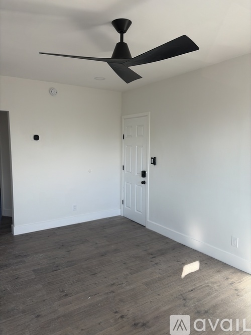A room with a ceiling fan and a door.