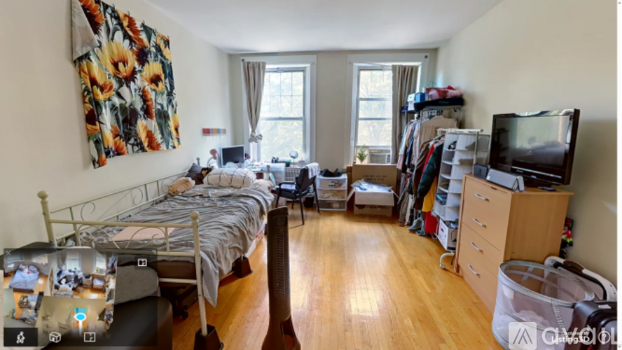 A bedroom with a bed, desk, and TV.