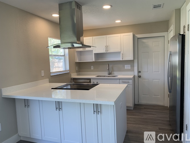A kitchen with white cabinets and a stainless steel refrigerator.