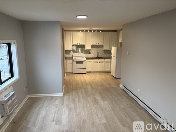 A spacious kitchen with white appliances and wooden flooring.