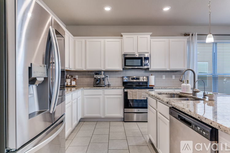 A modern kitchen with white cabinets and stainless steel appliances.