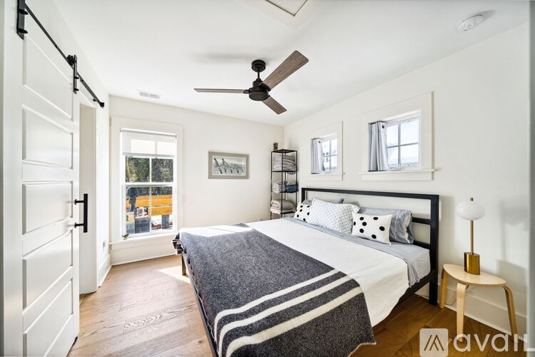 A bedroom with a bed, a ceiling fan, and a window.
