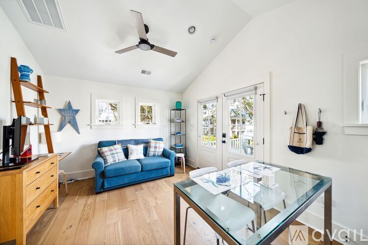 A living room with a blue couch and a glass coffee table.
