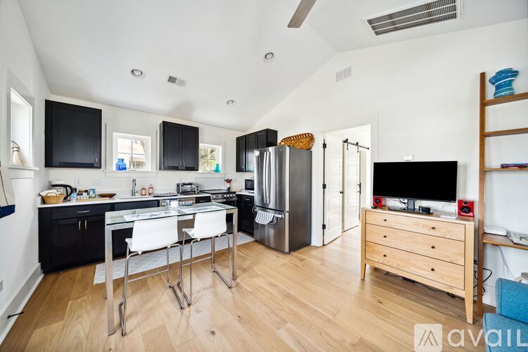 A kitchen with a refrigerator, sink, and a dining table with chairs.