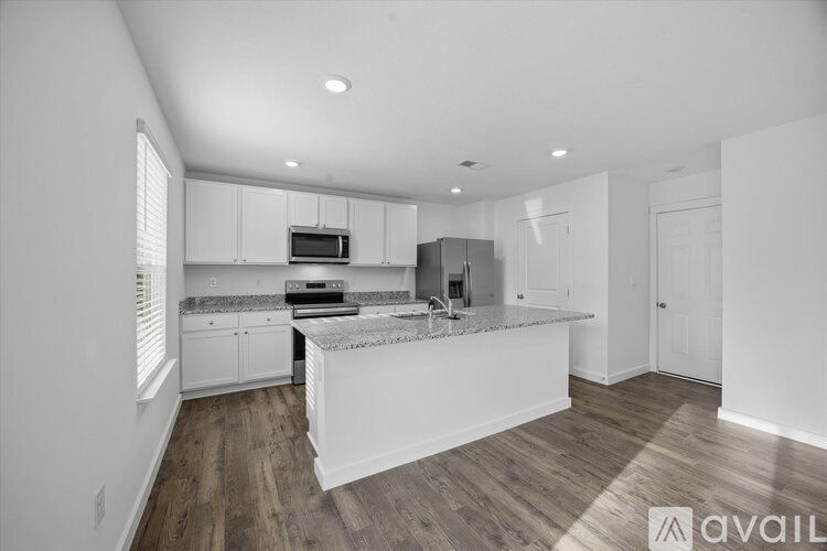 A modern kitchen with white cabinets and a wooden floor.
