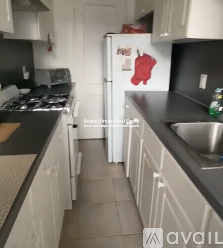 A kitchen with a white refrigerator and a red oven mitt magnet.